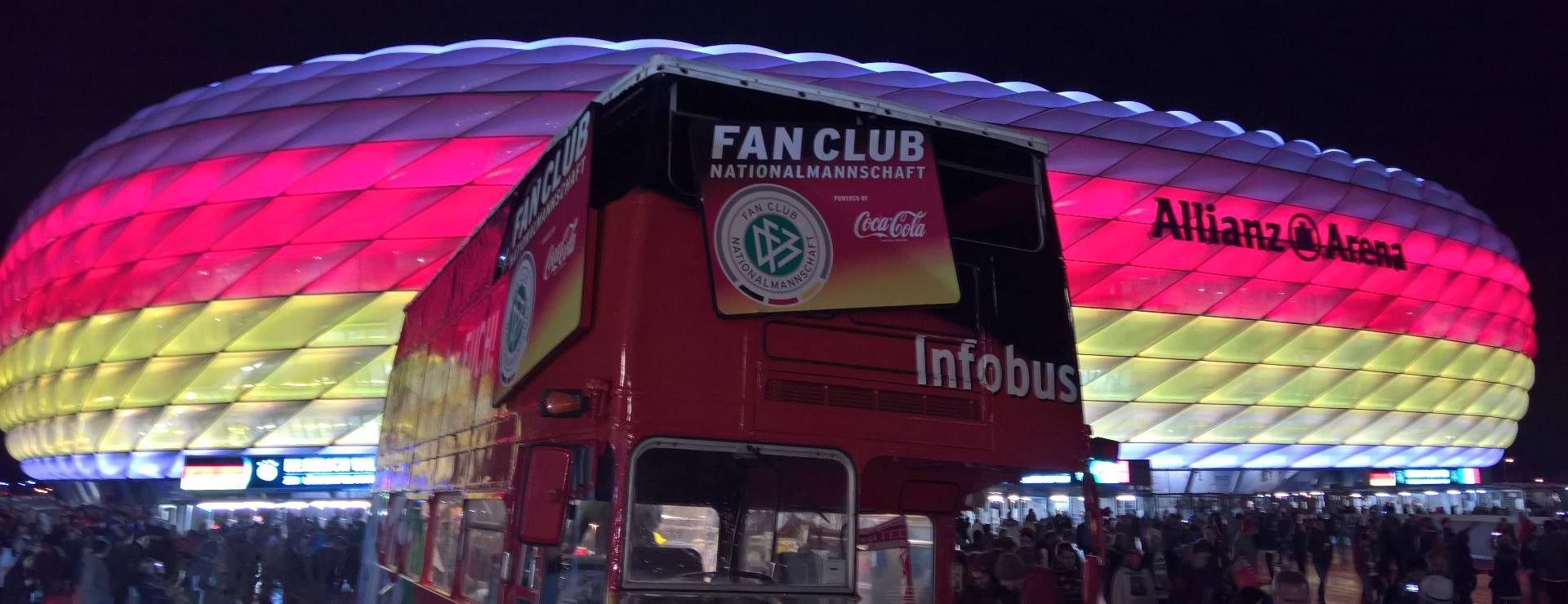 Der Fan Club-Bus vor der Allianz Arena, die in München in schwarz rot gold erscheint.